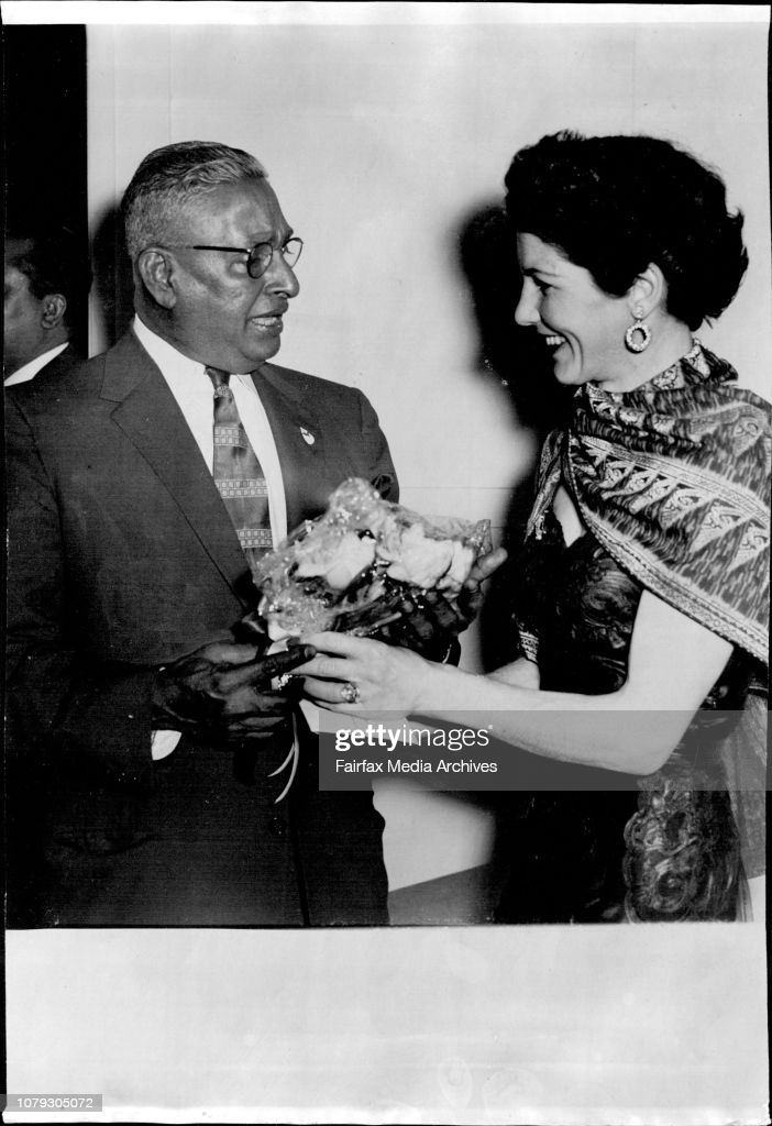 The Prime Minister of Ceylon, Sir John Kotelawala, before leaving Mascot tonight received from Mrs V K A H Read of Killara, the wife of the Commissioner of the Ceylon Tea Bureau of Australia and New Zealand, a bouquet of lotus flowers and a badge of the Teamakers Club of Australia admitting him to honorary membership of the club. November 17, 1955. (Photo by Frank Albert Charles Burke/Fairfax Media via Getty Images).